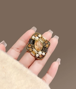 Macro view of vintage baroque square ring with amber stone and pearls on hand