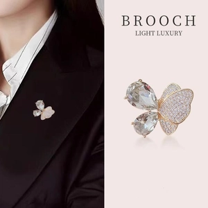 Broche papillon dorée élégante avec cristaux épinglée sur un blazer noir formel