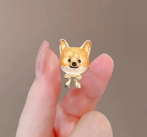 Gros plan d'une jolie broche chien Shiba Inu jaune avec finition dorée et petit nœud
