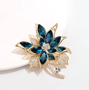 Detailansicht einer Blumenbrosche mit meeresblauen Kristallen und weißen Pavé-Diamanten