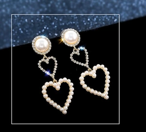Detail of silver drop earrings with heart-shaped pearls and sparkling rhinestones