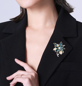 Eleganter Blumen-Brosche mit blauen Kristallen und weißen Diamanten auf schwarzem Anzug
