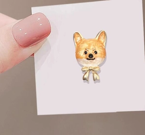 Détail d'une broche mignonne chien Shiba Inu avec nœud doré et finition émaillée