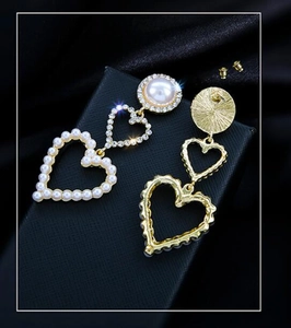 Macro view of heart-shaped earrings with pearls and rhinestones on black display box