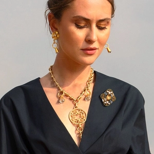 Detail of vintage rhombus brooch with amber gemstone and pearls on a model jacket