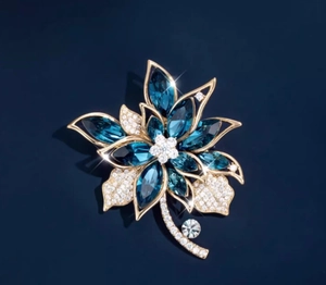 Detailansicht einer hochwertigen Blumenbrosche mit dunkelblauen Kristallen und Gold