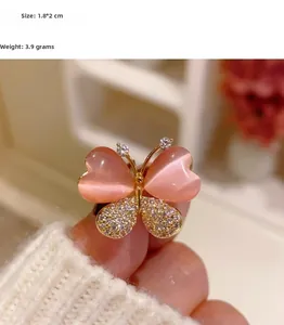 Gros plan détaillé d'une broche papillon en opale rose mesurant 1,8 sur 2 centimètres
