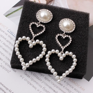 Detail of bridal drop earrings with pearls, rhinestones and heart-shaped pendants