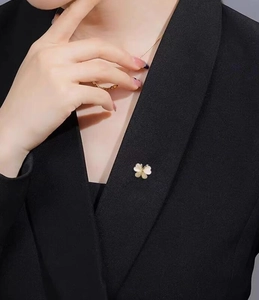 Détail d'une broche papillon dorée avec nacre blanche portée sur le revers d'un blazer
