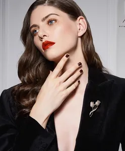 Détail d'une broche tulipe dorée avec diamants sur un blazer en velours noir