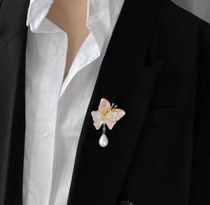 Broche papillon élégante aux ailes roses avec perle sur une veste de costume noire