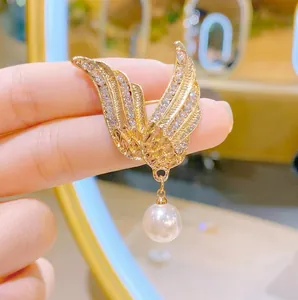 Goldene Engelsflügel-Brosche mit Zirkonia-Steinen und einer großen weißen Perle