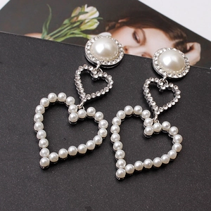 Detail of elegant heart drop earrings with pearls and rhinestones on a stylish background