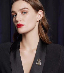 Close-up of golden hollow gourd brooch with white pearl on a black suit lapel