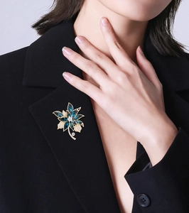 Nahaufnahme der goldenen Blumenbrosche mit tiefblauen Edelsteinen auf schwarzem Blazer
