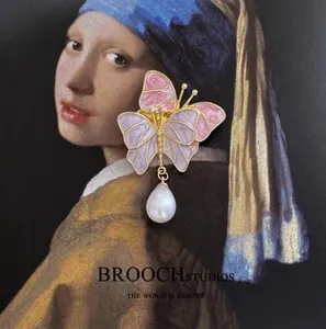 Broche papillon vintage en émail rose avec perle goutte posée sur une peinture classique