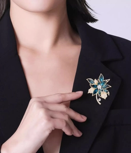 Detailansicht der Blumenbrosche mit blauen Kristallen an einem dunklen Blazer