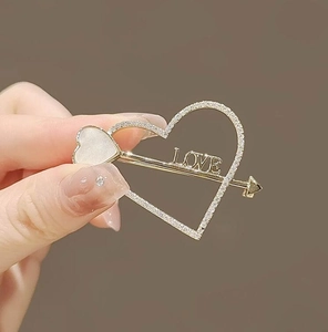 Dettaglio del fermaglio per capelli a freccia di Cupido con strass e scritta LOVE