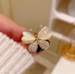 Gros plan détaillé d'une broche papillon dorée avec des pierres œil de chat et des cristaux