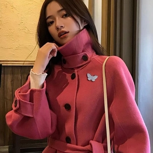 Spilla a farfalla argentata su un cappotto di lana rosa con bottoni neri