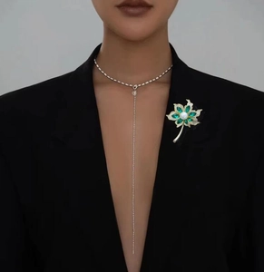 Détail d'une broche de luxe avec pierres marquises vertes et perle sur le revers d'un costume
