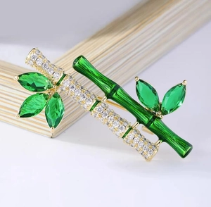 Close-up of bamboo brooch with green marquise crystals and white pave stones