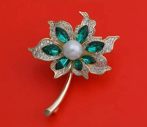 Détail de la broche palmier avec cristaux verts, perle blanche et métal doré