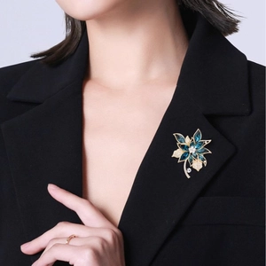 Eleganter goldener Blumenanstecker mit dunkelblauen Kristallen am schwarzen Revers