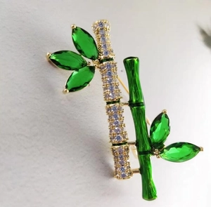 Macro detail of a bamboo brooch with green marquise stones and zircon pavé inlay