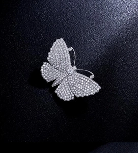 Macro di una spilla a farfalla con zirconi bianchi su sfondo in pelle scura elegante