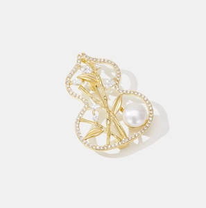 Detailed view of gourd-shaped brooch with bamboo leaf motifs and a large white pearl