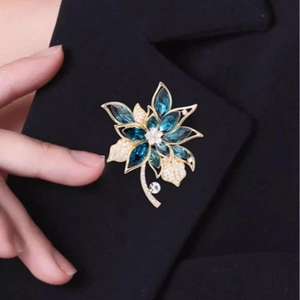 Eleganter Gold-Blumen-Brosche mit blauen Edelsteinen und Zirkon auf schwarzem Blazer