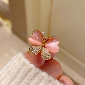 Détail de la broche papillon en pierre œil de chat rose avec ailes dorées et zircons