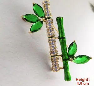 Detailed close-up of a bamboo brooch with green marquise crystals and golden plating