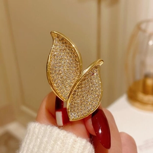 Macro detail of elegant gold leaf brooch featuring dense cubic zirconia pavé stones