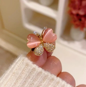 Vue macro d'une broche papillon en pierre œil de chat rose avec cristaux et cadre doré
