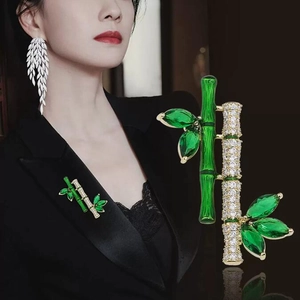 Bamboo pin brooch with green crystals and gold base shown on clothing and in detail