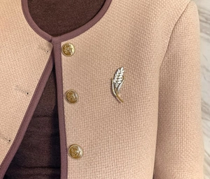 Vue détaillée d'une broche épi de blé avec strass et opale sur une veste en tweed