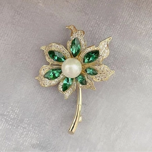 Broche de cocotier luxueuse avec perle blanche, cristaux verts et base en feuilles dorées
