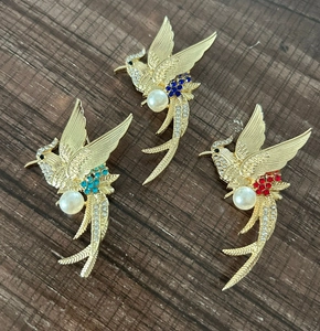 Detailed close-up of bird brooches with gold alloy, crystals and white pearls