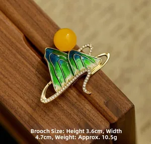 Detail of mountain-shaped brooch with green enamel, gold edges, and crystal accents