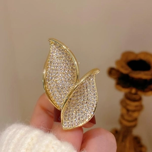 Elegant gold leaf earrings encrusted with sparkling zircons held by a hand