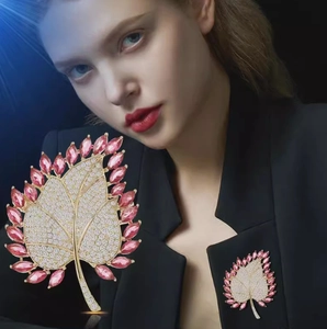 Elegant gold maple leaf brooch with pink gems and crystals pinned on black blazer