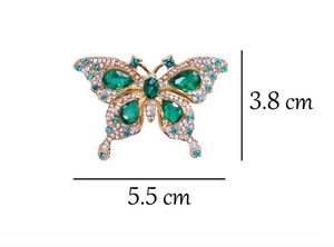 Macro detail of emerald butterfly brooch with teardrop gems and blue rhinestones