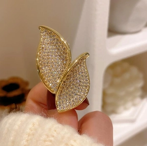 Elegant gold leaf brooch with pavé crystal diamonds on a beige knitted sweater