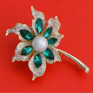 Broche luxueuse cocotier avec cristaux verts et perle sur un fond rouge vif
