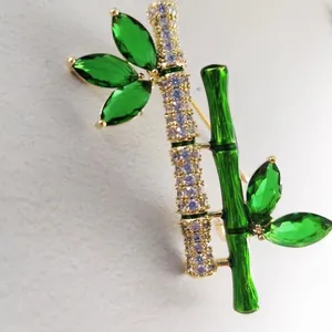 Bamboo brooch with green crystals and sparkling zircons set in golden alloy finish