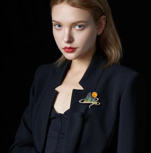 Detail of green enamel landscape brooch with gold trim on black suit lapel