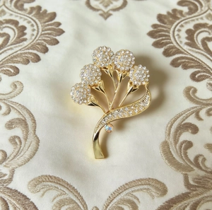 Détail de la broche florale dorée de luxe avec strass pavés sur tissu de soie