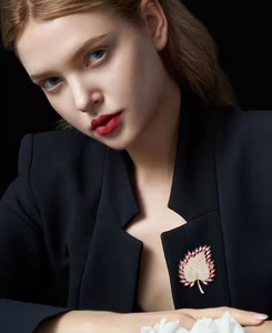 Detail of maple leaf brooch with pink gems and crystals on a black suit blazer